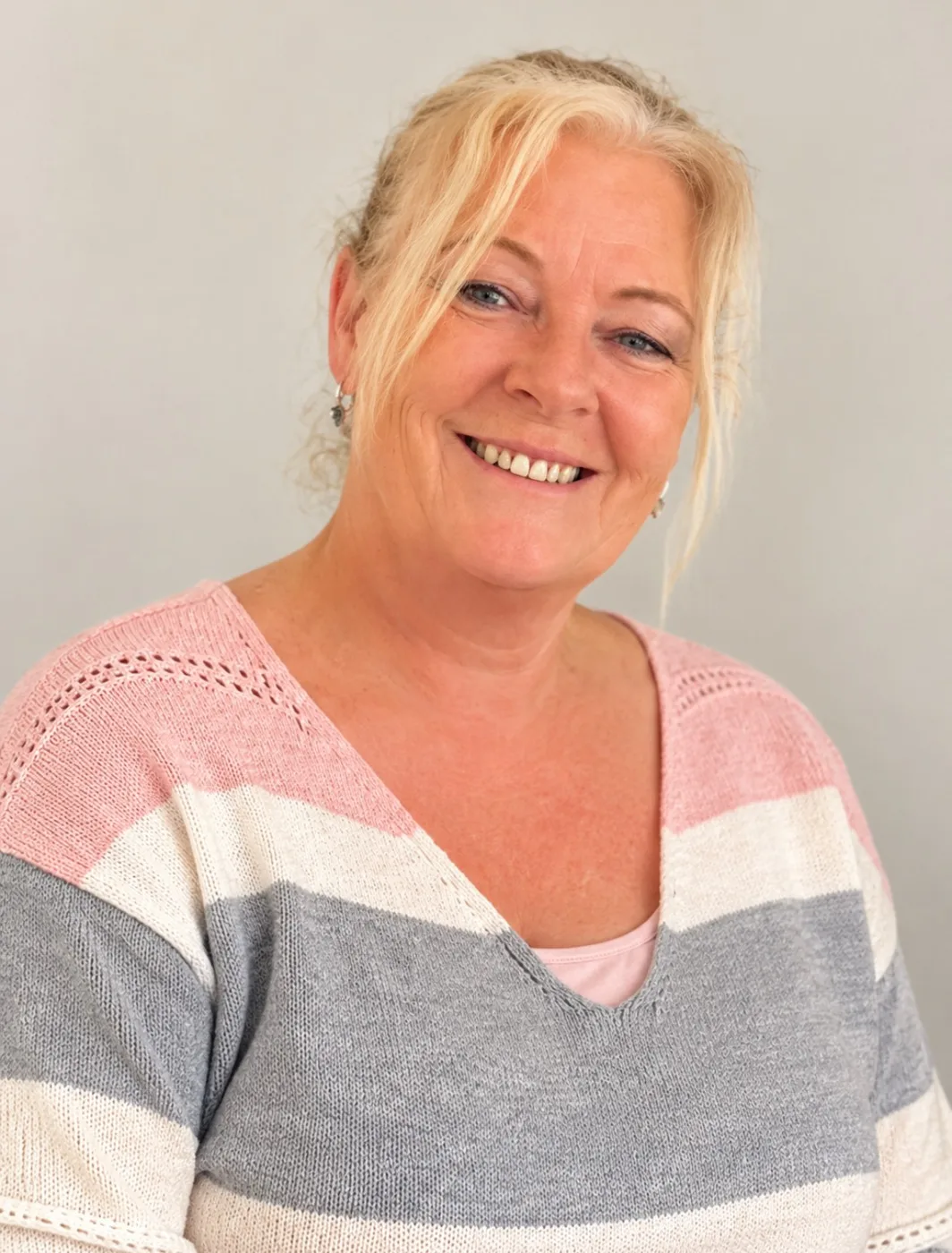 Yvonne Mckinnon smiling, wearing a pink, grey and white striped jumper