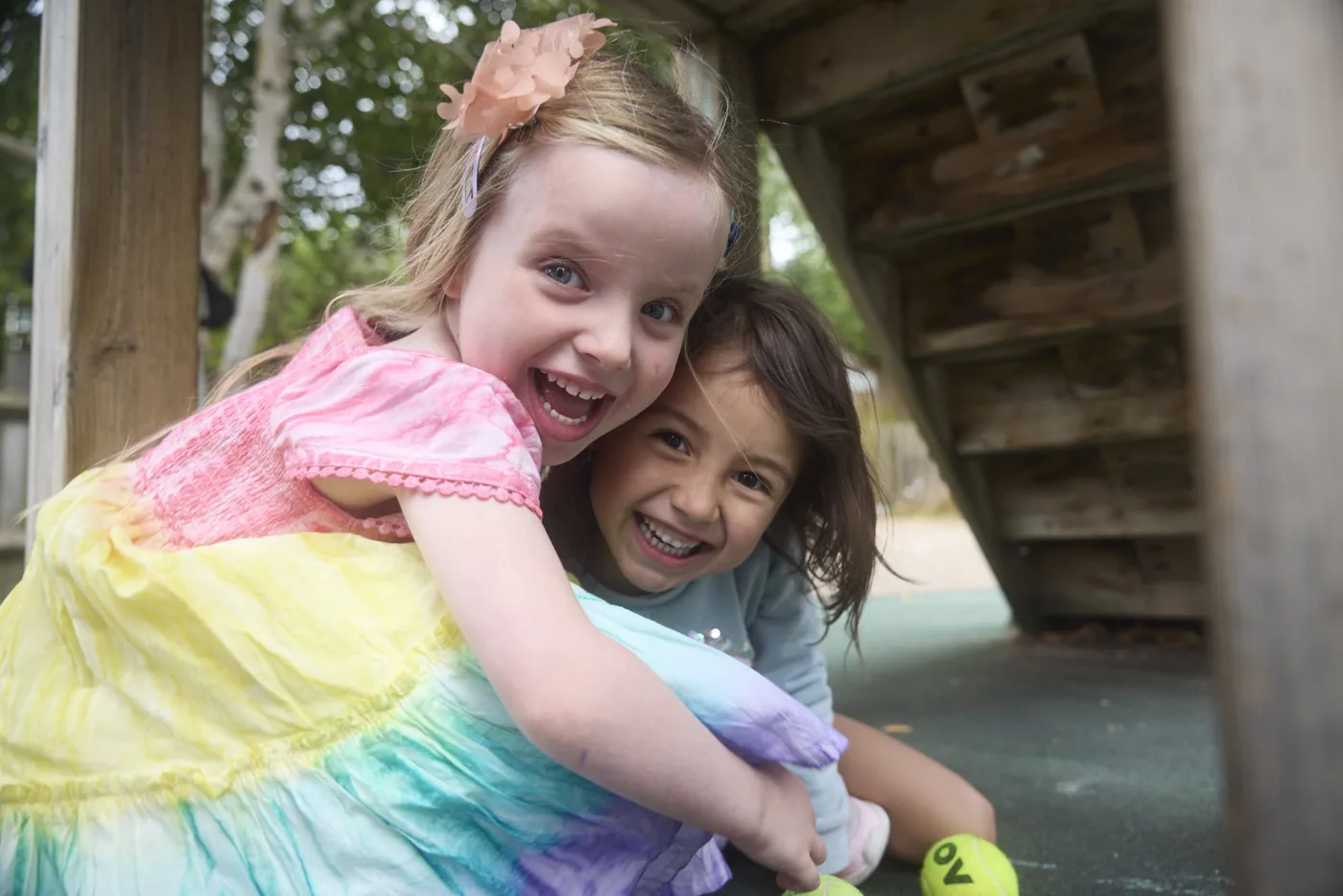 Two young girls hugging and laughing in a play area